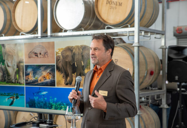 John Baker, Chief Program Officer at WildAid, holds a microphone as he addresses an audience.